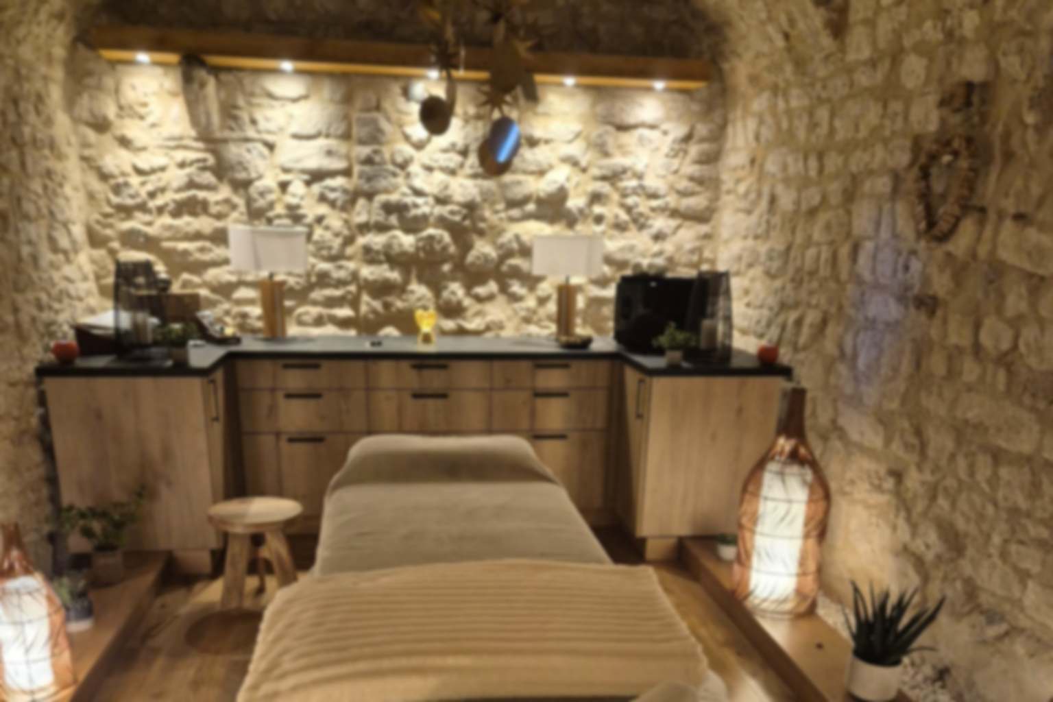 Cabinet de réflexologie de Carine Laugier : table de soin dans une cave voûtée en pierre éclairée d'une lumière chaude, à Saint-Michel-l'Observatoire